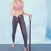 Woman using 8-section resistance stretch band for yoga and Pilates, enhancing flexibility and strength on exercise mat.