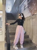 Stylish girl wearing pink loose sports pants with headphones, showcasing a trendy look. Perfect for casual outings and active days.
