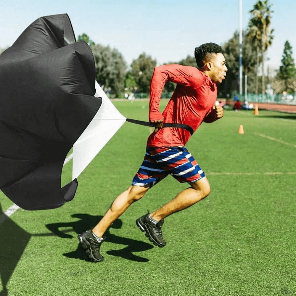 Athlete using a resistance parachute during training on a grassy field, part of the Pro Speed and Agility Training Set SF3167.