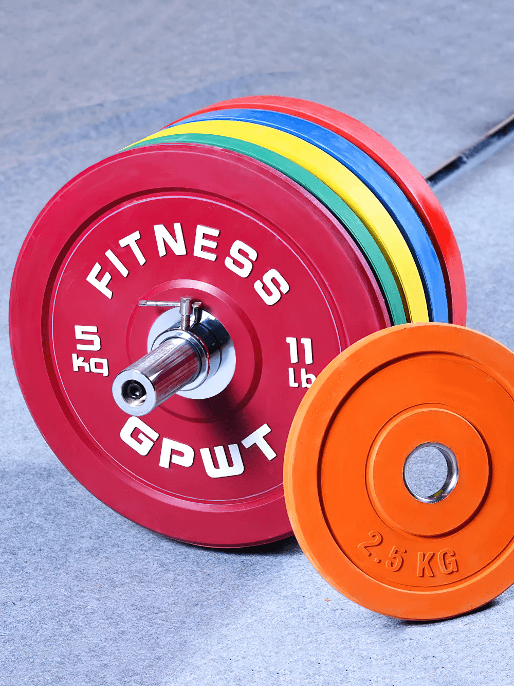Color-coded rubber barbell weight plates on a gym floor, featuring durable design for strength training, suitable for all athletes.
