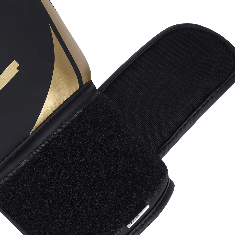 Close-up of black boxing glove with gold accents and secure hook-and-loop closure for training and sparring.