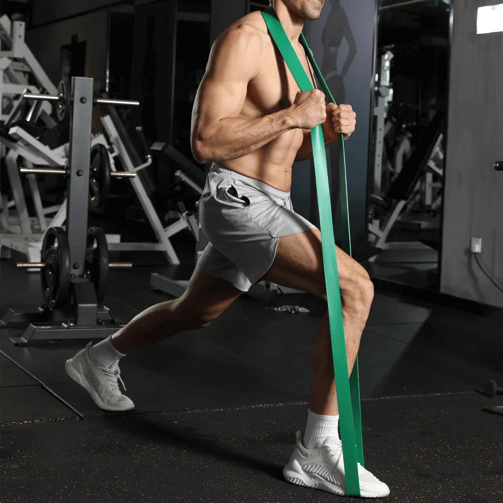 Man using green pull-up resistance bands for strength training in gym, enhancing mobility and flexibility with durable workout gear.