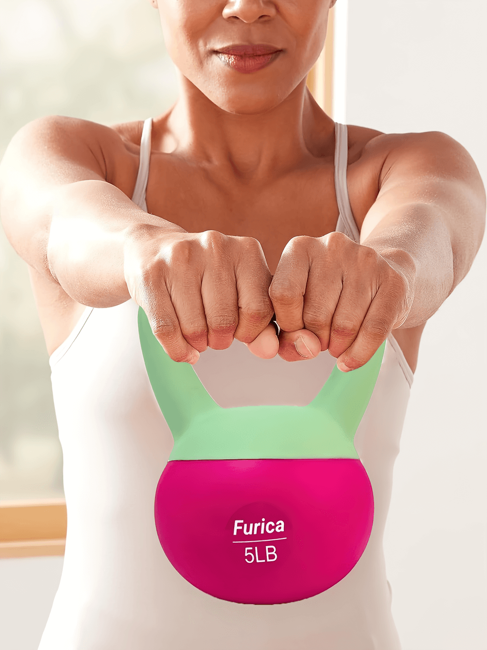 Woman lifting a 5lb pink and green kettlebell during a workout session