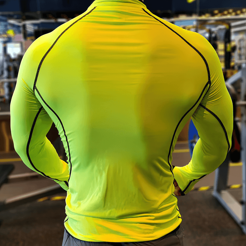 Back view of neon yellow quarter-zip long sleeves compression bodybuilding top worn by a man in a gym.