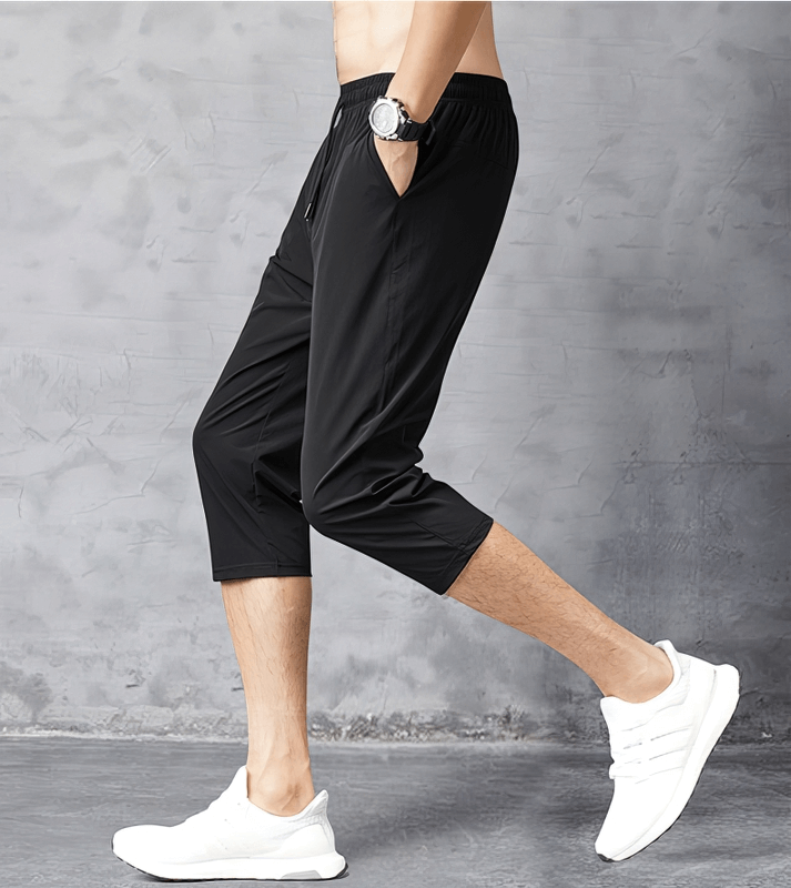 Man wearing black quick dry lightweight men's extended shorts with side pockets, perfect for casual outings and active lifestyle.