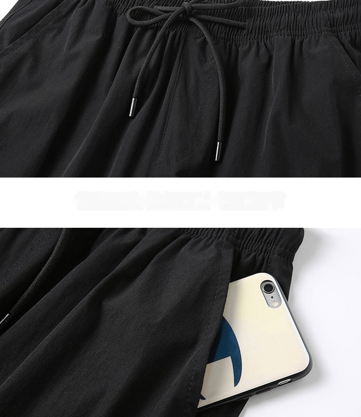 Black quick-dry men's shorts with drawstring and side pocket holding a smartphone, showcasing comfort and functionality.