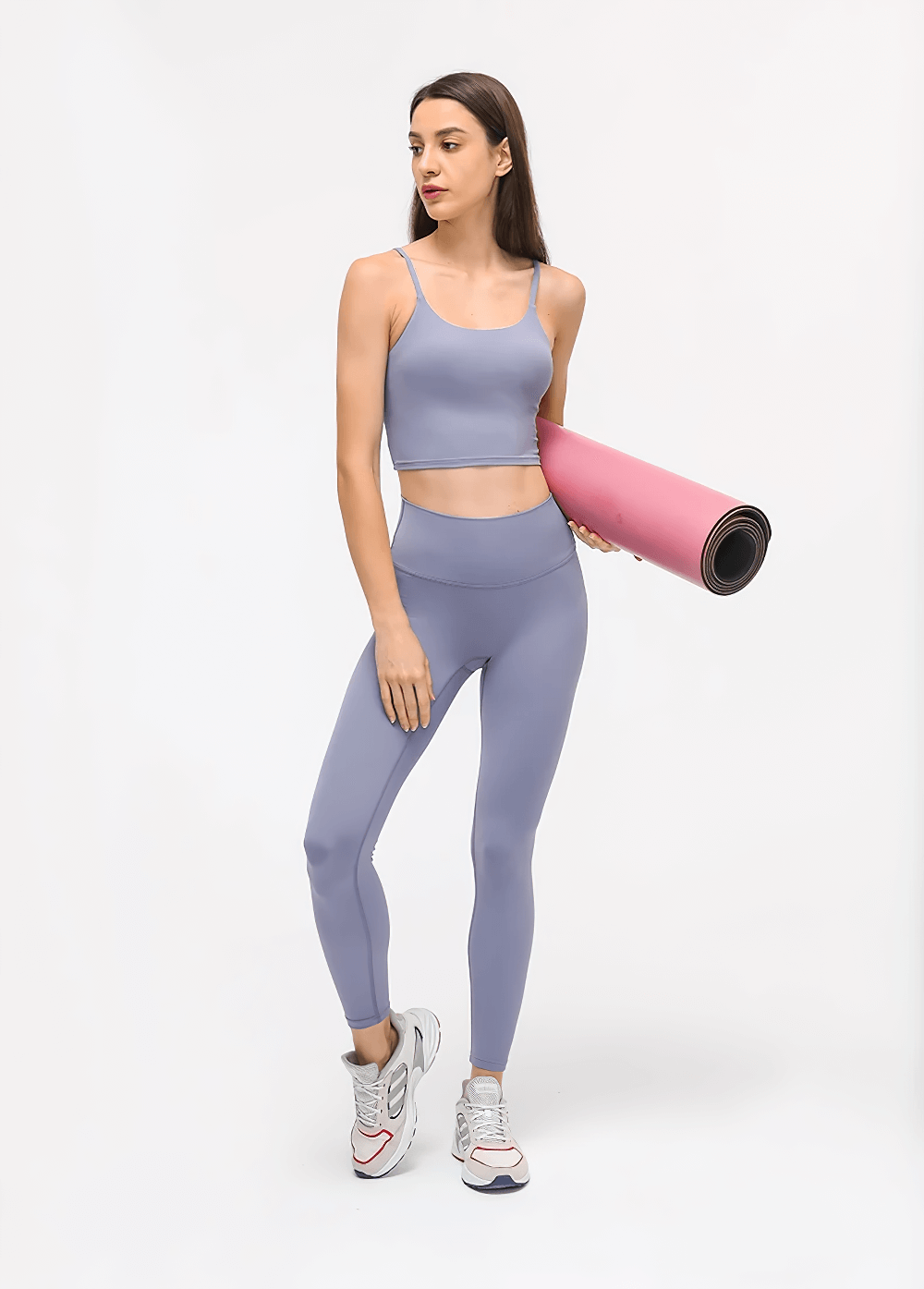 Woman wearing Quick Dry Solid Color Sleeveless Yoga Set in purple, holding pink yoga mat, showcasing eco-friendly 2-piece outfit.