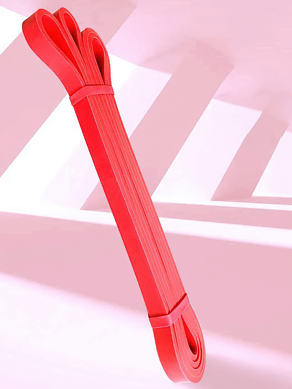 Red heavy duty resistance band for pull ups and stretching against a modern geometric backdrop.