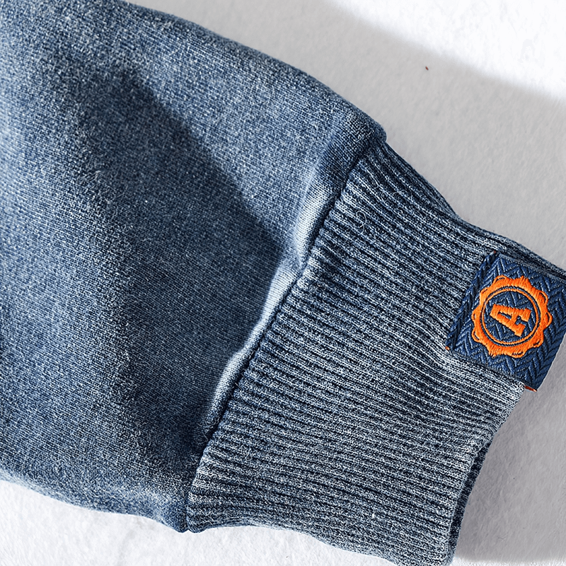 Close-up of sleeve detail on a blue knitted sports pullover for men, showcasing ribbed cuff and orange patch - SF1296.