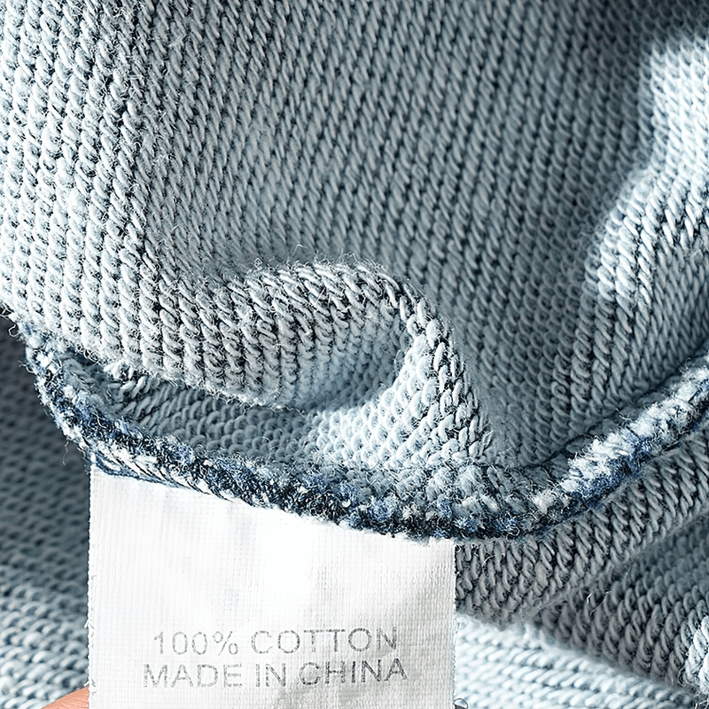 Close-up of thick knitted cotton fabric with care label, showcasing quality material in men's long-sleeved sports pullover.