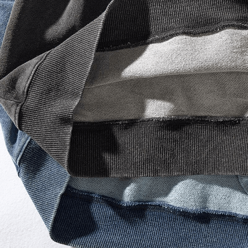 Close-up view of different colored knitted sports pullovers for men, showcasing thick cotton material and loose fit.