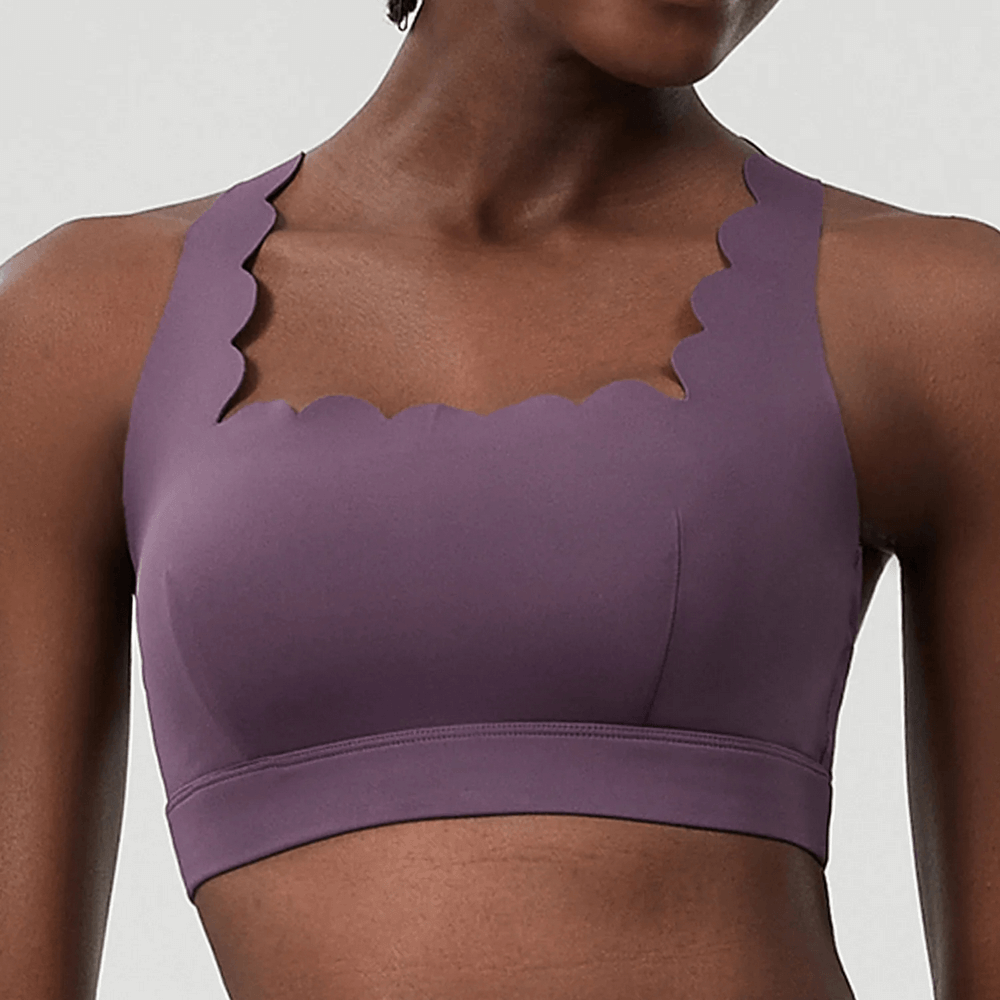 Woman wearing purple Scallop Crossback Sports Bra with Removable Pads - SF4000 showcasing scallop-edge and crisscross back design.