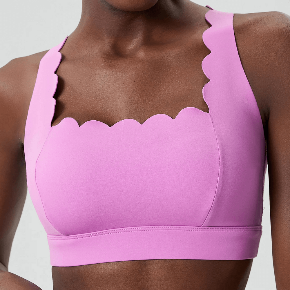 Model wearing bright pink Scallop Crossback Sports Bra with Removable Pads - SF4000 showing scallop-edge and wave neckline design.
