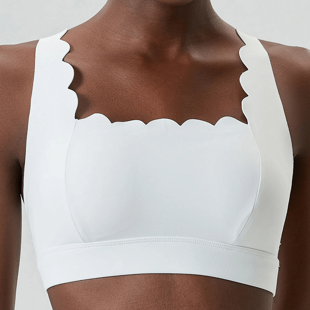 Close-up of sporty white Scallop Crossback Sports Bra with Removable Pads - SF4000 featuring scalloped edges and smooth fabric.