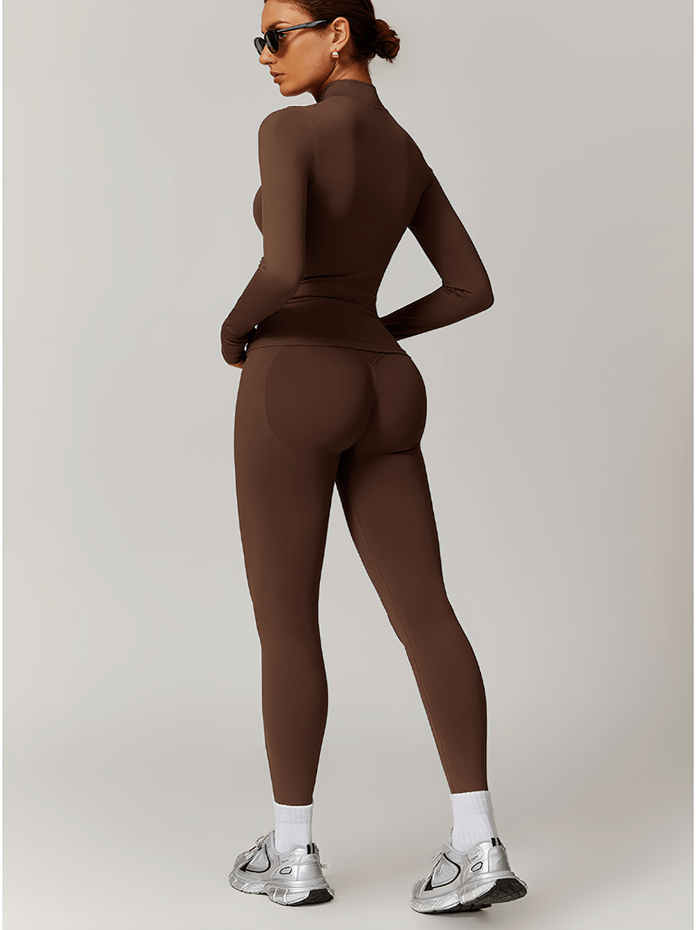 Woman wearing seamless full-length activewear set with thumbholes in brown, showcasing back view and athletic fit for yoga or gym.