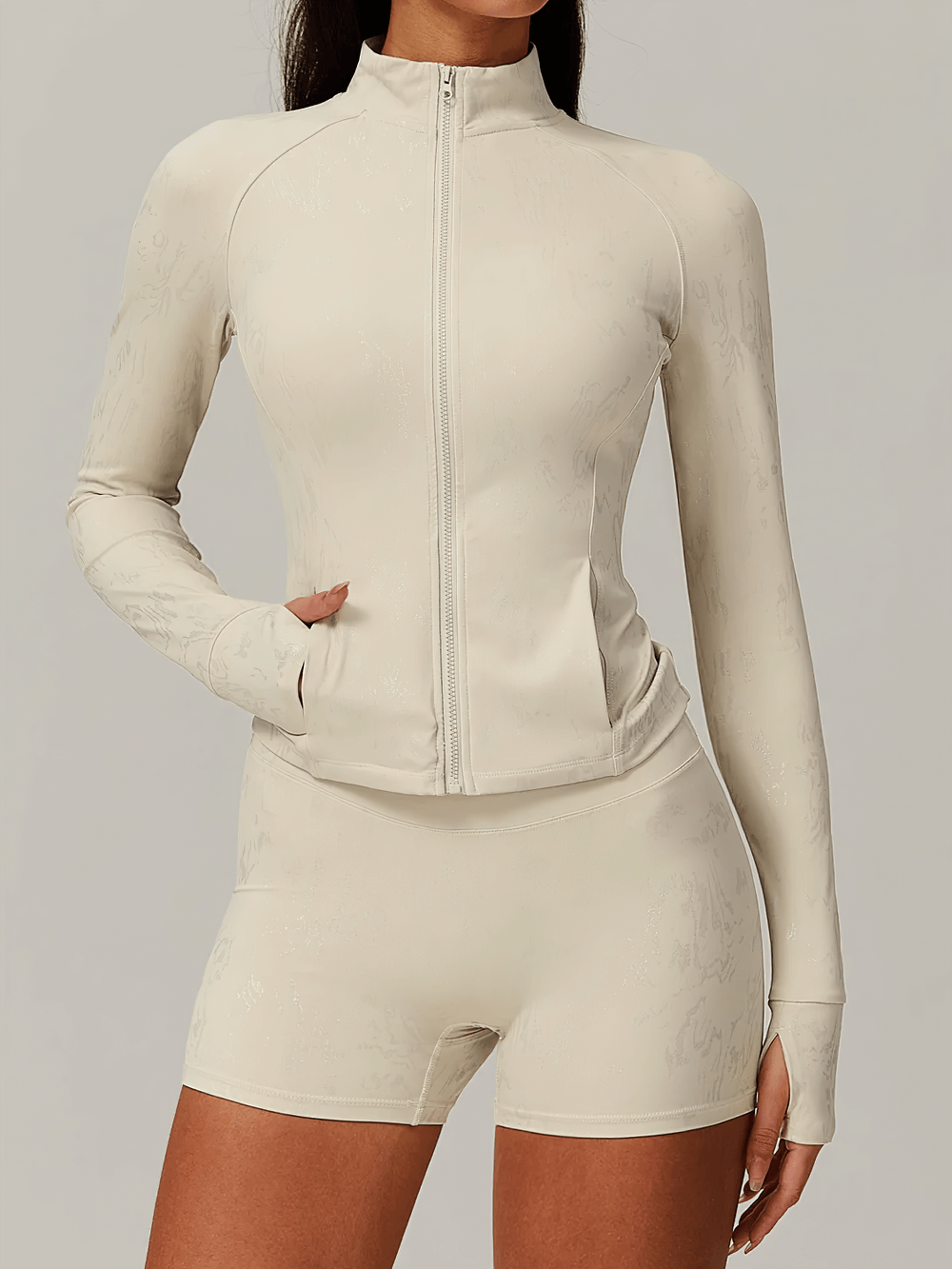 Woman in beige seamless full-zip active jacket and shorts set SF2403 with thumbholes, high-stretch and high-waist design.