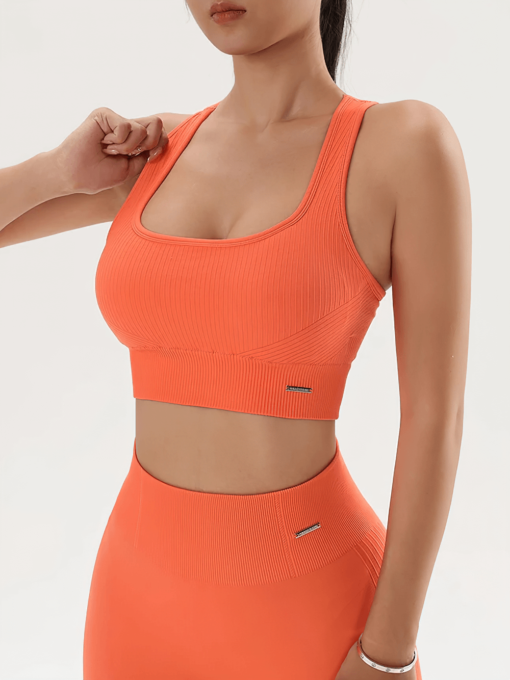 Woman wearing Seamless Ribbed Sports Bra with Racerback Support - SF4042 in orange, showcasing ribbed texture and racerback design.