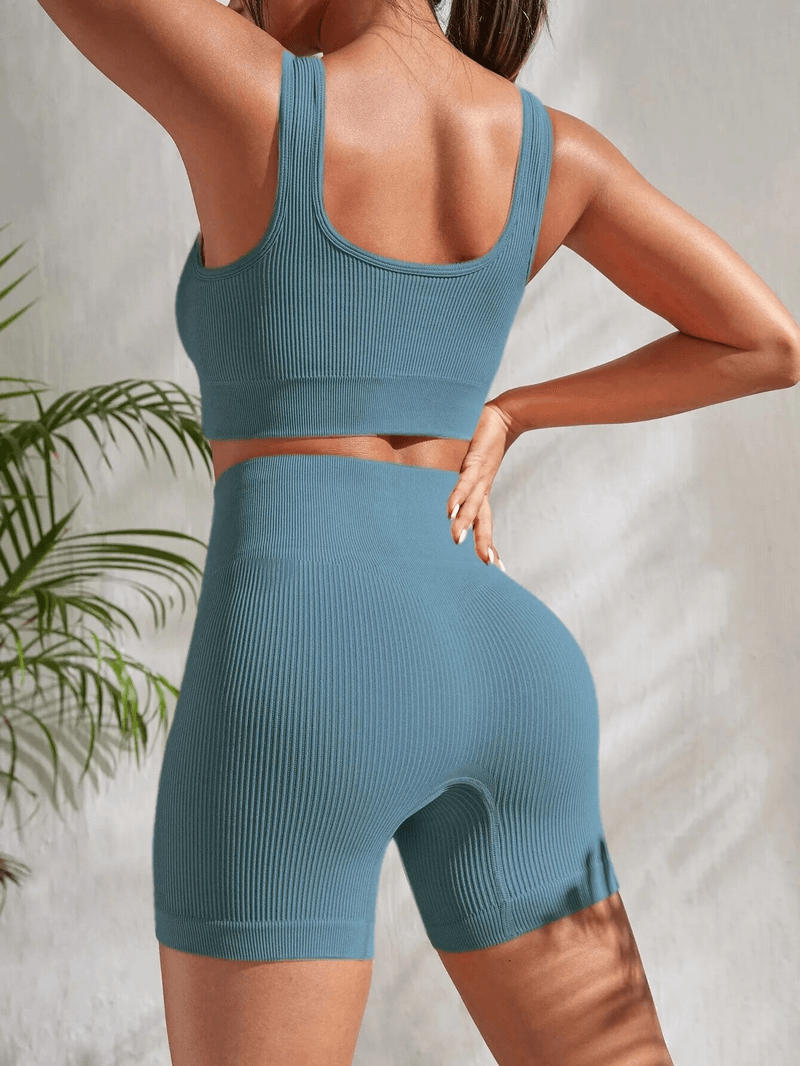 Woman wearing seamless ribbed yoga crop top and high waist shorts set in blue, designed for comfort and mobility during workouts.