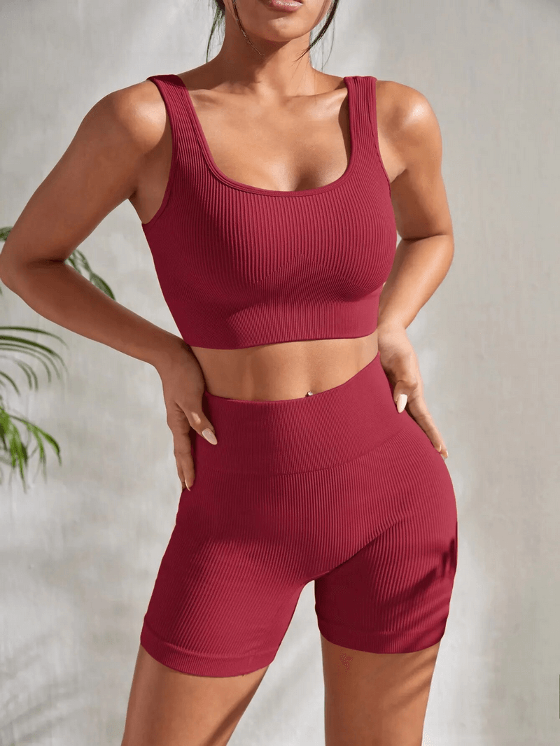 Woman in seamless ribbed yoga crop top and high waist shorts set, color burgundy, perfect for workouts and yoga. Model standing confidently.