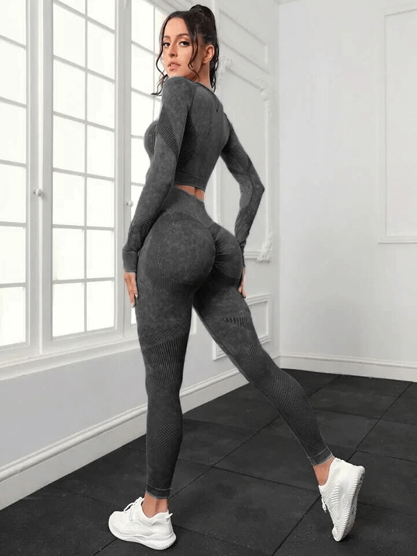 Woman wearing seamless high waist pants and long sleeve top in grey, perfect for yoga, showing back view, flexible fit in a bright studio.