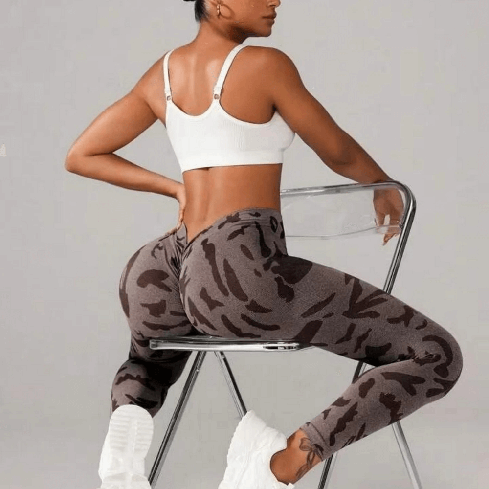 Model wearing Seamless V-Waist Camo Yoga Leggings with Scrunch - SF4010, seated on a chair showcasing back view and tie dye print.