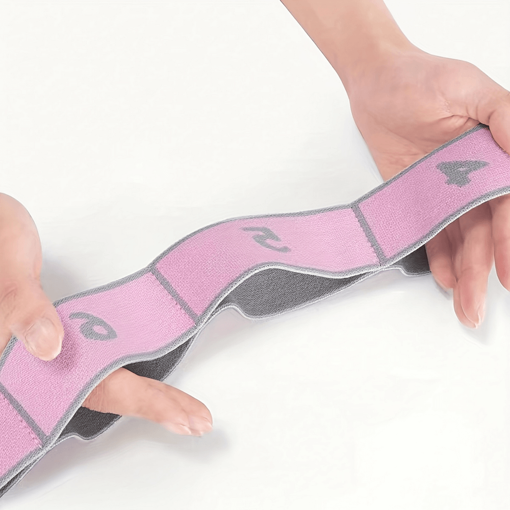 Holding a pink segmented resistance strap for flexibility and strength training, enhancing yoga and pilates exercises.