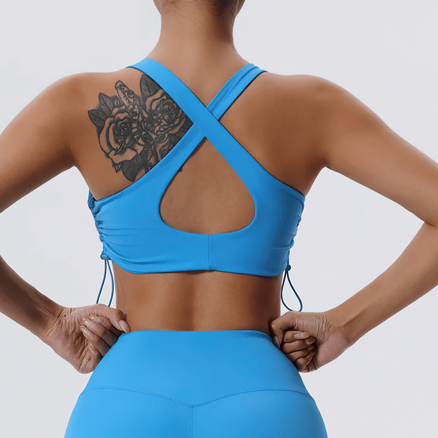 Back view of a woman in a blue adjustable sports bra with a stylish breathable design, showcasing fitness fashion elegance.