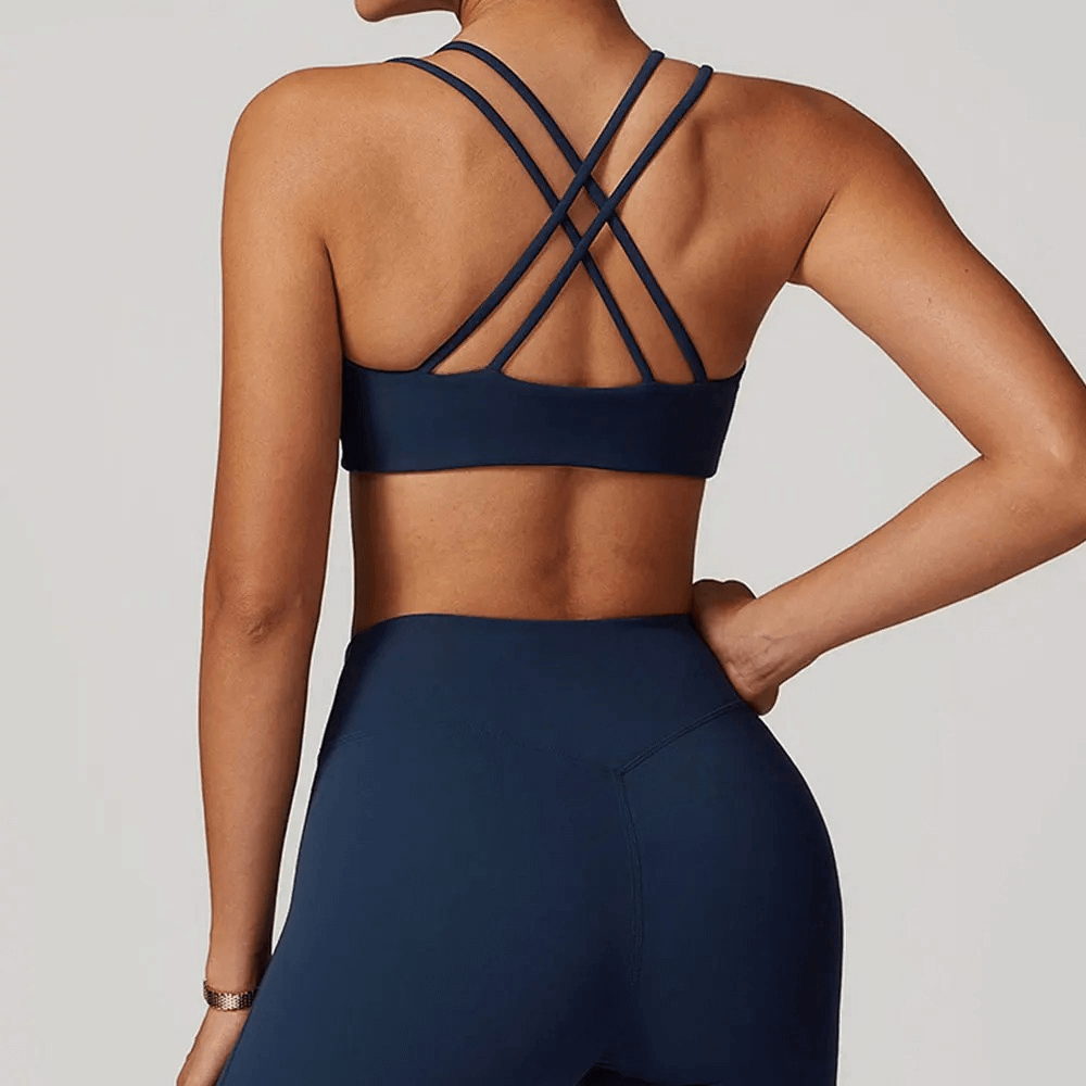 Back view of woman wearing a sexy criss-cross strap sports bra for high support in navy, perfect for gym workouts and active routines.