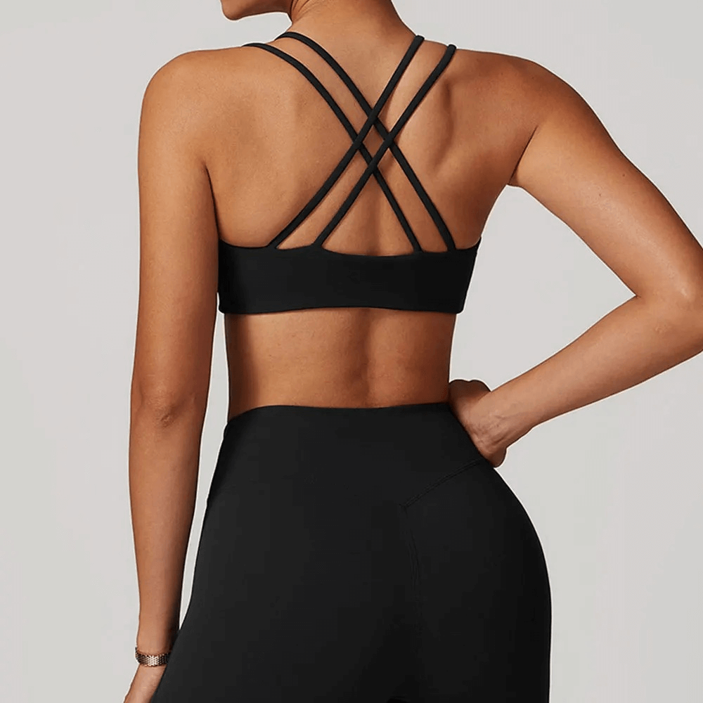 Back view of woman wearing black criss-cross strap sports bra, showcasing sleek design and high support for active workouts.