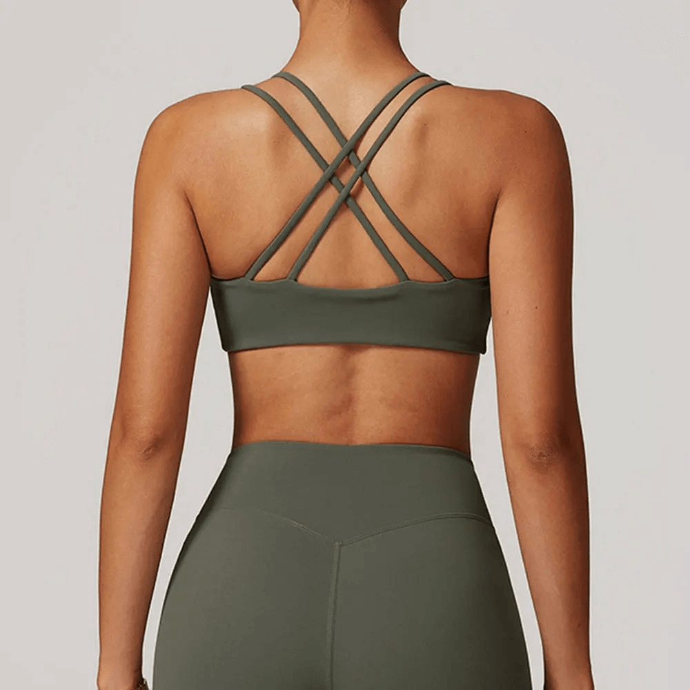 Back view of woman wearing sexy criss-cross strap sports bra in green, designed for high support and comfort in fitness activities.