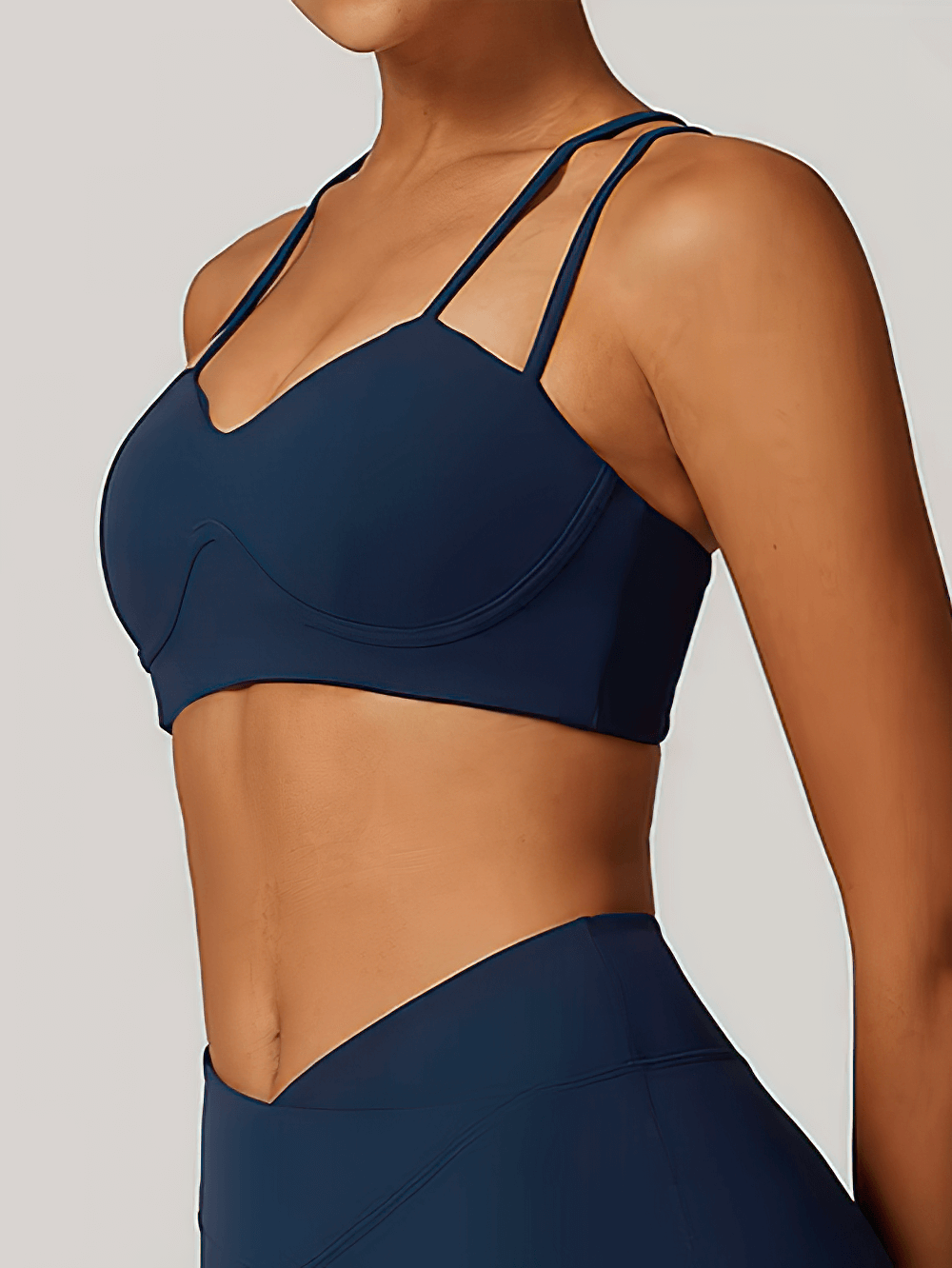 Woman wearing a navy blue criss-cross strap sports bra, perfect for high support during workouts like yoga and running.