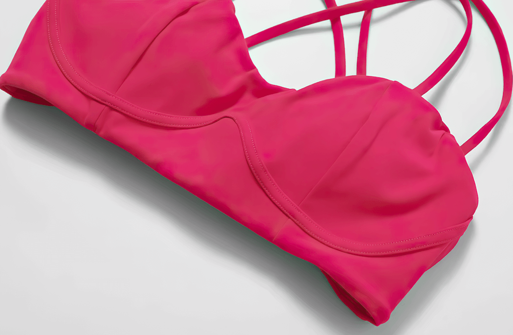 Sexy criss-cross strap sports bra in pink with high support, ideal for running and fitness. Breathable, quick-dry, nylon-spandex fabric.