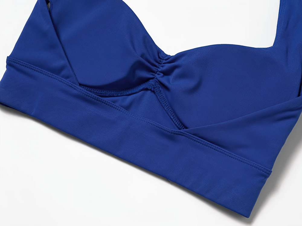 Stylish blue racerback sports bra with padded support and elastic band for active wear.