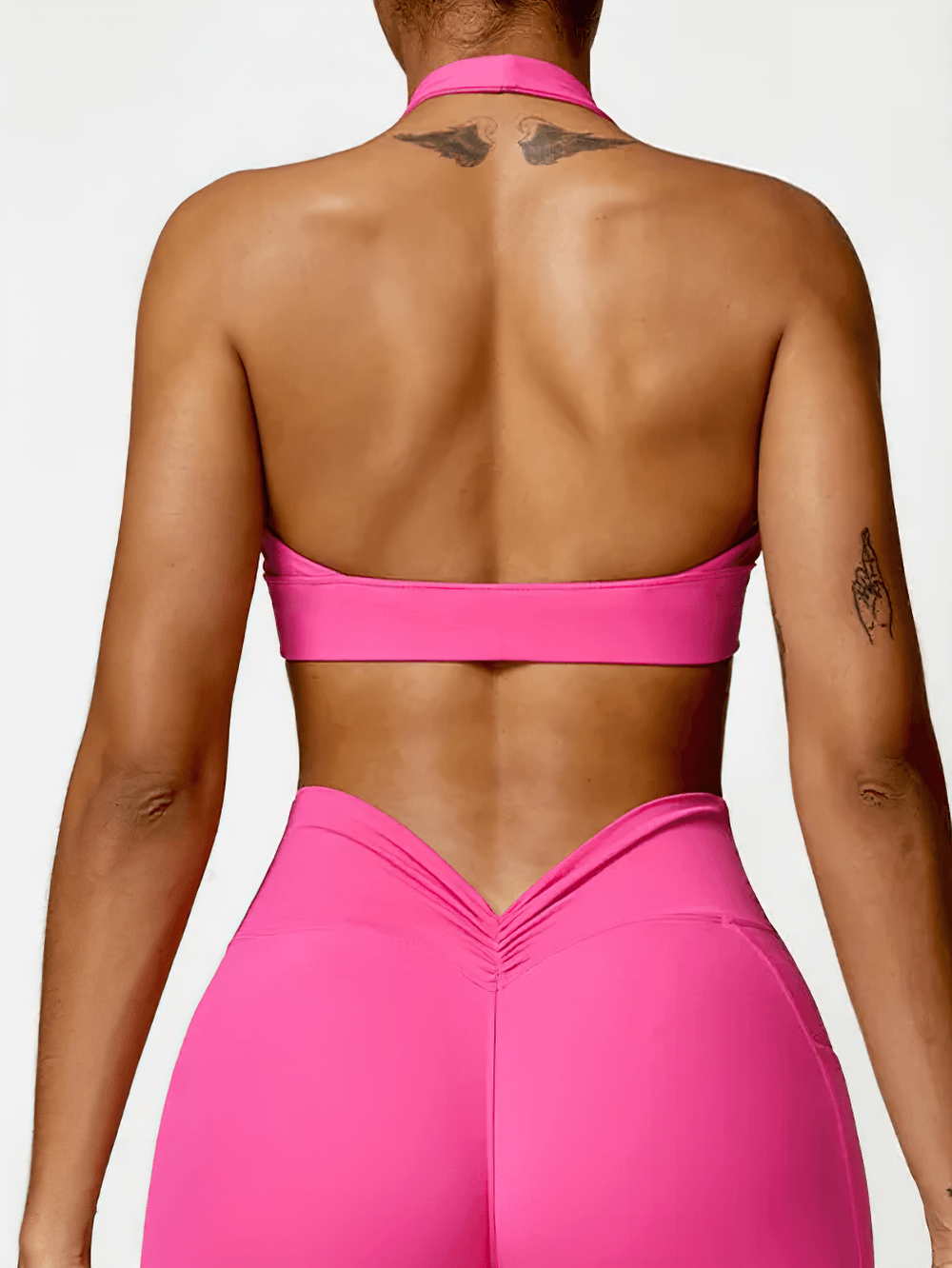 Back view of woman wearing pink racerback sports bra and leggings, showcasing stylish athletic design and supportive fit for workouts.