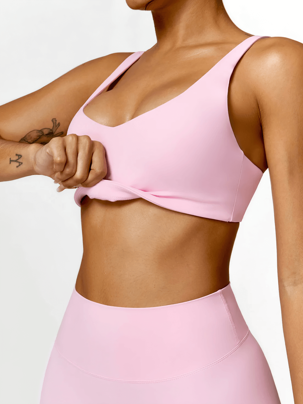 Woman wearing a pink strappy sports bra with square neckline, showing breathable, stretchy fabric. Perfect for yoga and workouts.