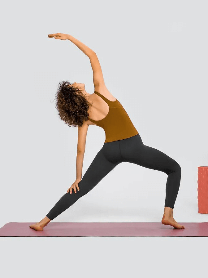 Woman practicing yoga in sexy V-neck tank top with padded bra, showcasing flexibility and style on a yoga mat.