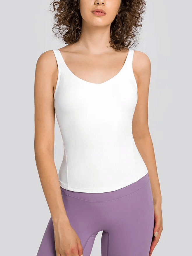 Model wearing a sexy V-neck yoga sports tank top with padded bra in white, paired with purple leggings, showcasing breathable nylon-spandex fabric.
