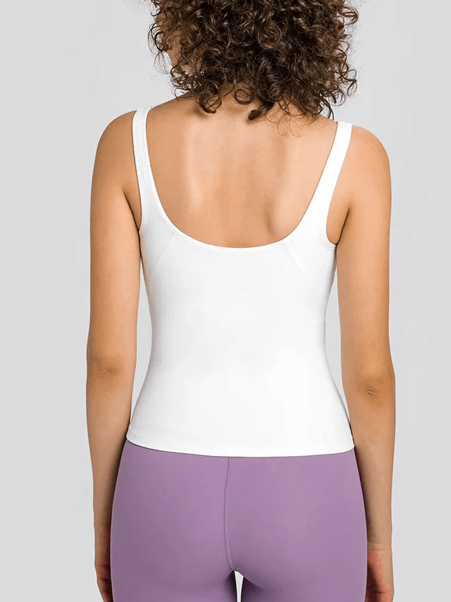 Back view of woman wearing white V-neck yoga tank top and purple leggings showcasing comfortable workout wear.