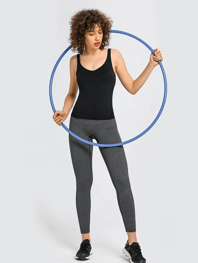 Woman in black V-neck yoga sports tank top with padded bra holding a hoop, showcasing flexible and comfortable activewear.