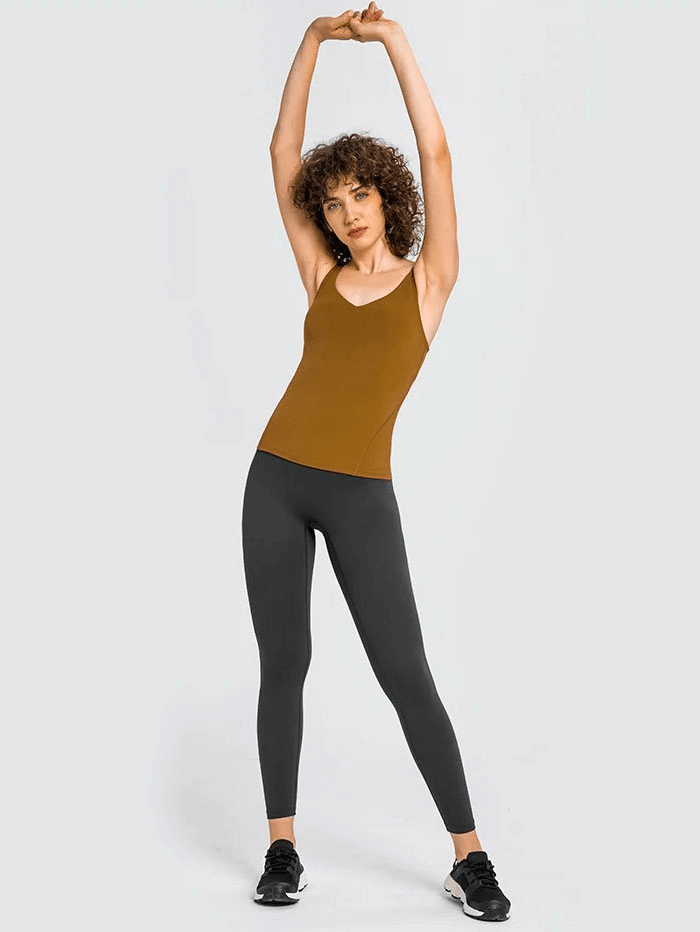 Woman stretching in brown V-neck yoga sports tank top and black leggings