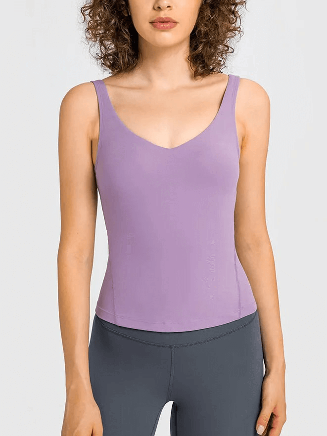 Woman wearing a purple V-neck yoga sports tank top with padded bra, showcasing a sleek sleeveless design for comfort and support.