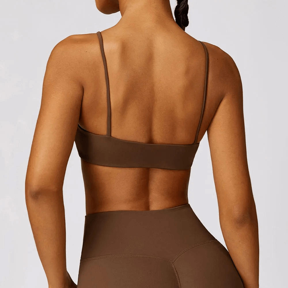 Back view of woman wearing shockproof yoga sports bra, brown, with adjustable straps, nylon-spandex blend for gym and fitness activities.