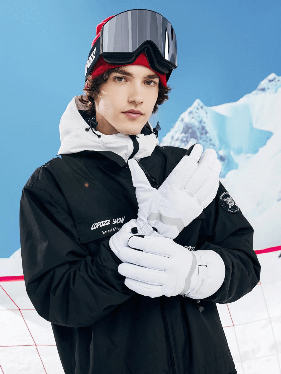 Person wearing black jacket and white ski gloves against snowy mountain backdrop, showcasing wristband holder gloves for skiing.