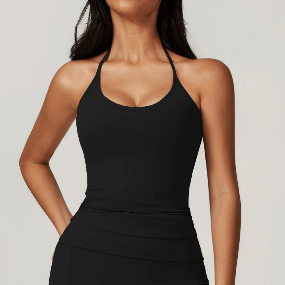 Woman wearing sleek black halter neck sports tank for yoga and training, showcasing stylish design and support.