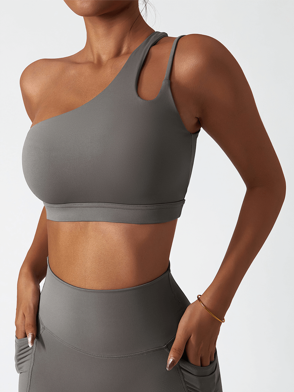 Sleek one-shoulder sports bra in gray for active wear, made from breathable nylon-spandex, offering stylish support during exercise.