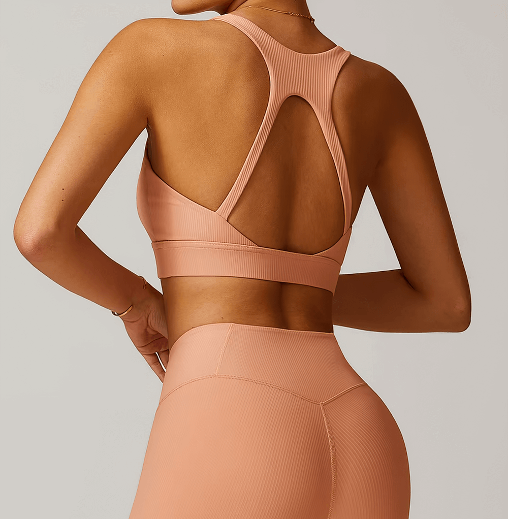 Woman wearing a sleek ribbed backless sports bra, ideal for running, yoga, and dancing. Breathable nylon-spandex blend, open-back design.
