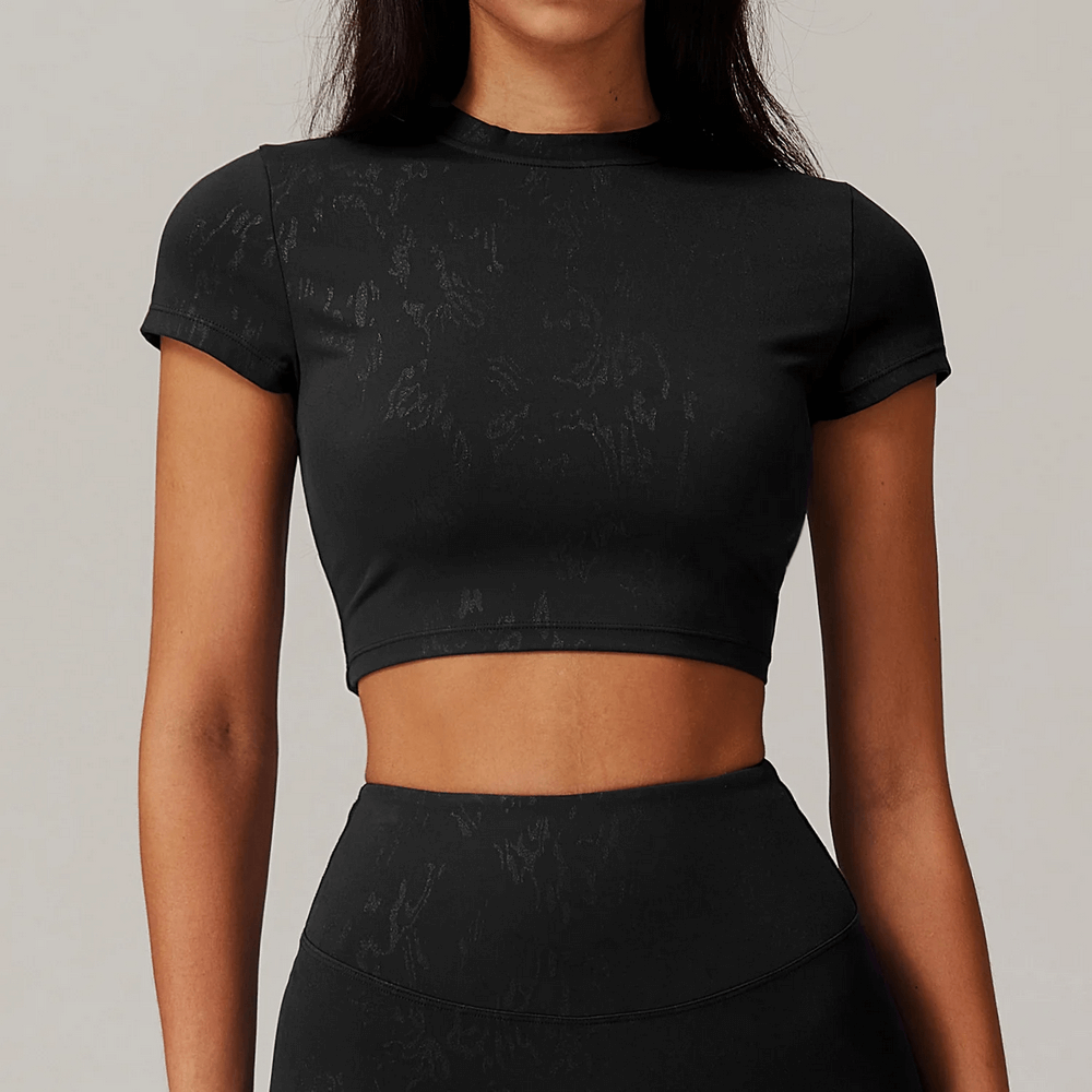 Woman wearing sleek short-sleeve cropped active top in black for gym or casual wear.