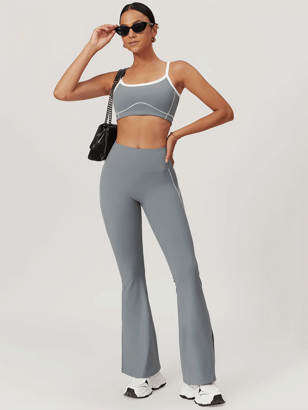 Woman modeling sleek yoga flare pants and top set, perfect for active wear and sports. Stylish and versatile gym outfit in gray.