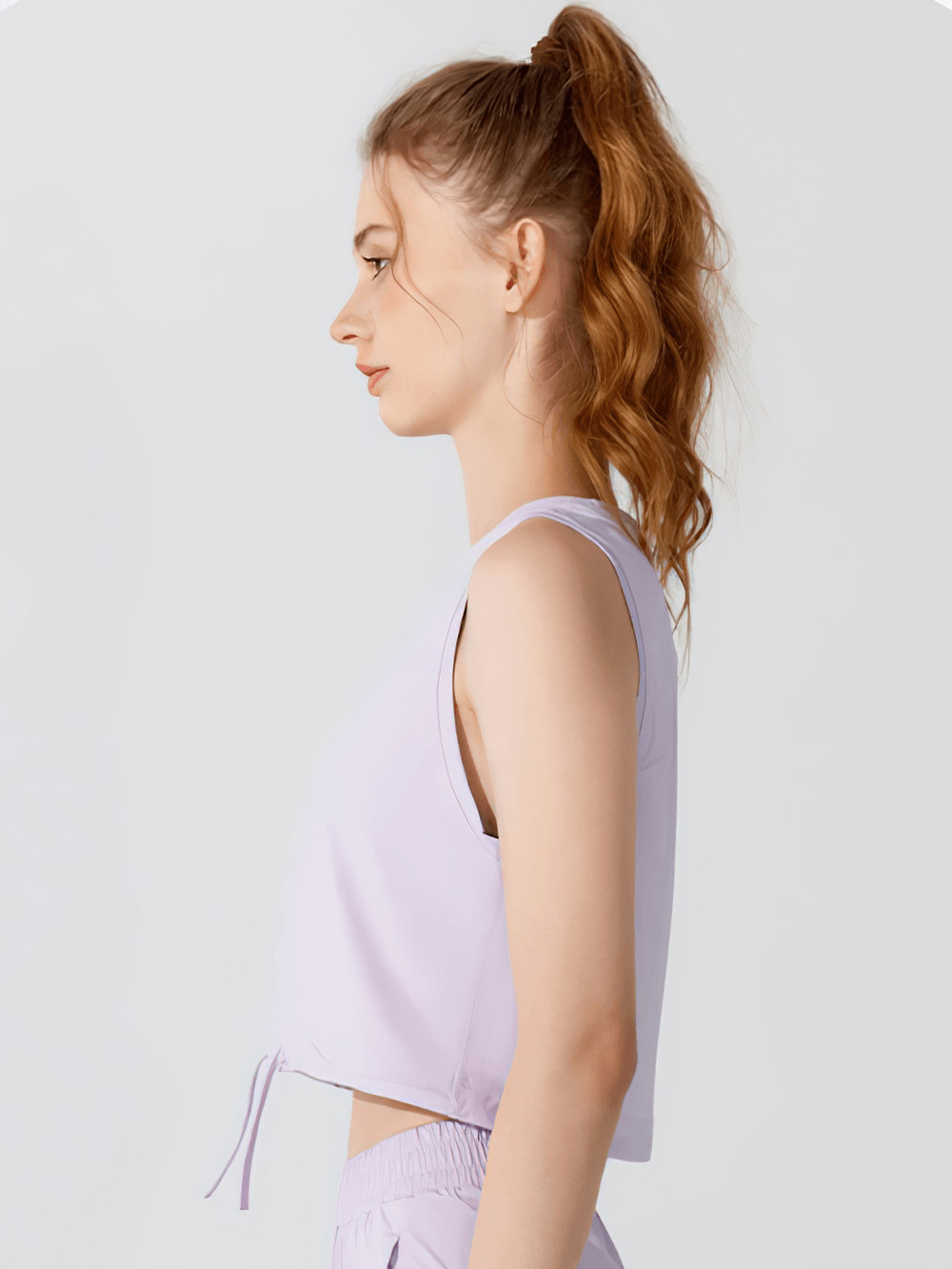 Side view of woman in a sleek lavender yoga tank top with drawstring detail, perfect for gym and yoga.