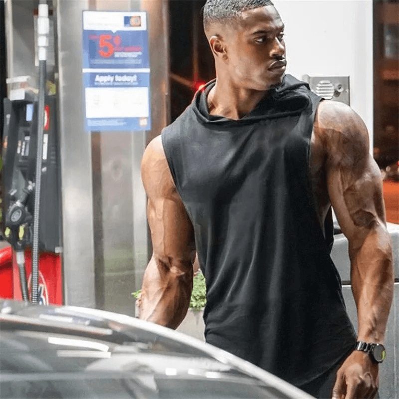 Man wearing Sleeveless Hooded Gym Tank Top for Men SF2000 at a gas station, showcasing athletic build and casual style.